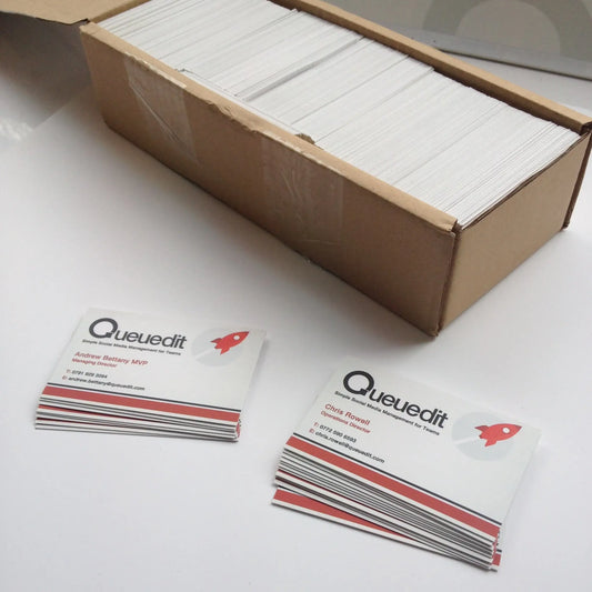 Stack of printed business cards and cardboard box on white table, commercial print service