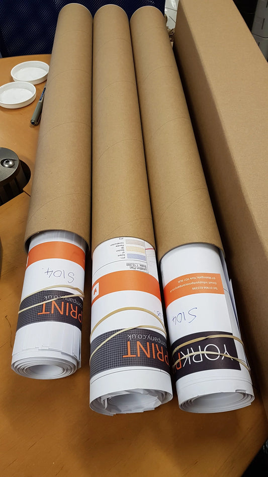 Rolled printed posters in brown cardboard tubes on a table, ready for same-day printing.