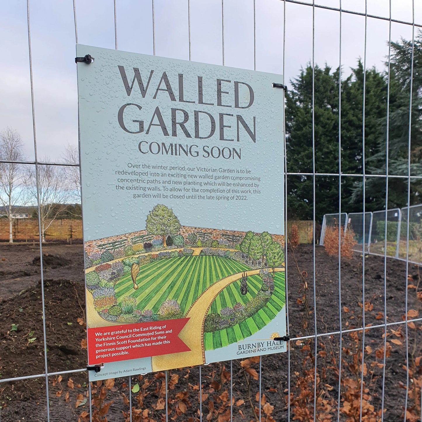 Drilled Foamex sign for walled garden renovation, displayed on metal fence at outdoor site