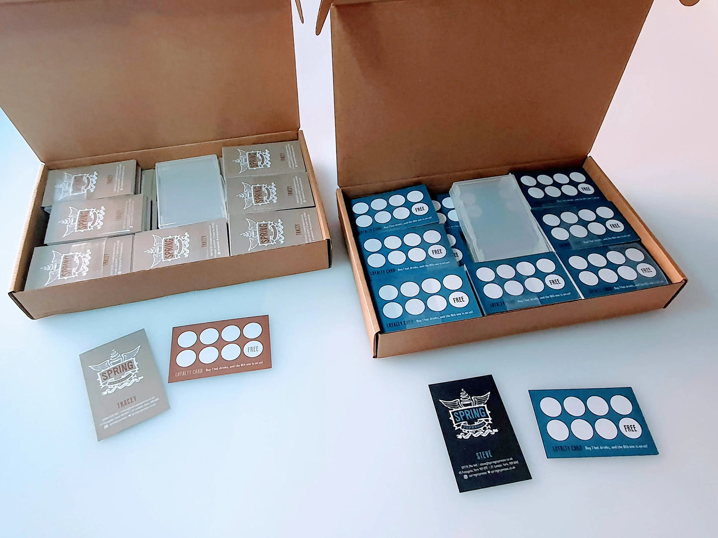 Printed loyalty cards in boxes on a white table, showcasing custom card designs.