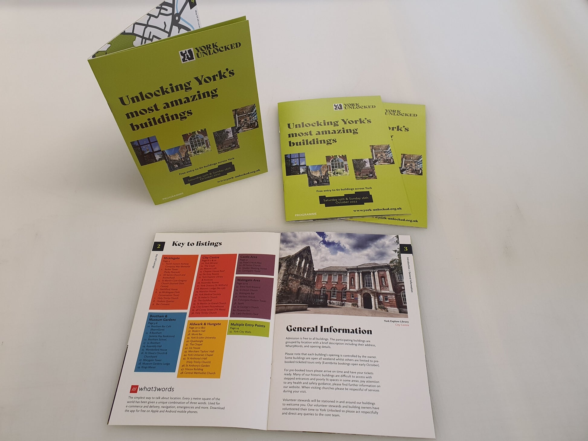 Assorted York city event brochures and an open booklet on a white surface, featuring building photos and information.